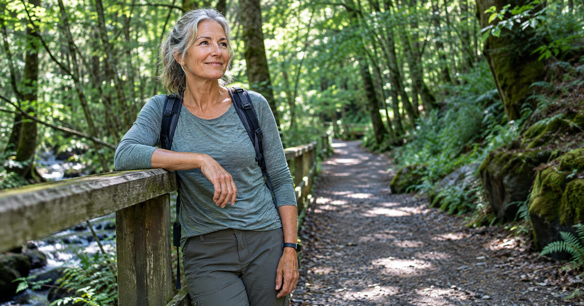 Mature woman hiking on a forest trail, representing an active lifestyle, wellness, and confidence during menopause.