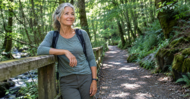 Mature woman hiking on a forest trail, representing an active lifestyle, wellness, and confidence during menopause.